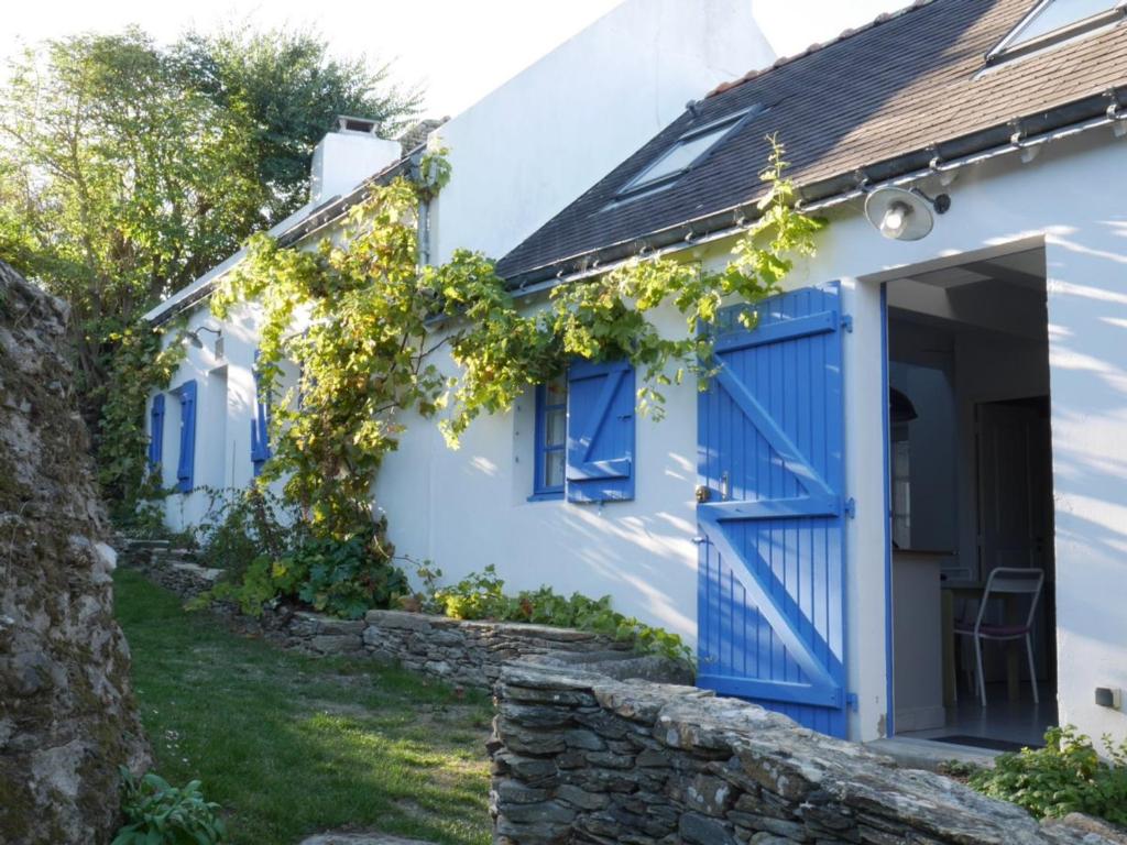 une porte bleue sur une maison blanche avec des vignes dans l'établissement Charmante maison proche plage à Locmaria, 4 pers, jardin, cheminée, équipements complets - FR-1-418-97, à Locmaria