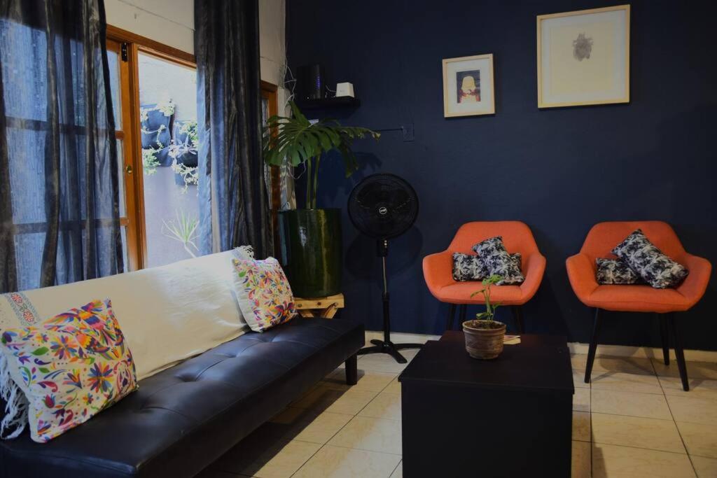 a living room with a couch and two orange chairs at Espacioso moderno y bien ubicado in Oaxaca City