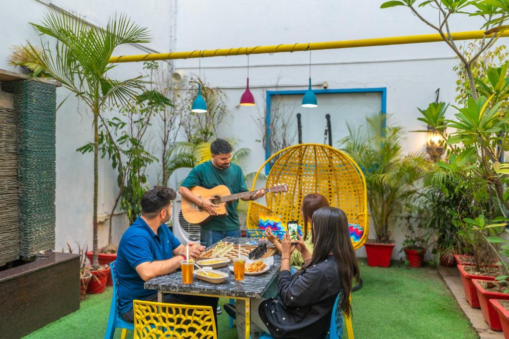 Un groupe de personnes assises autour d'une table jouant de la guitare dans l'établissement goSTOPS Delhi, à New Delhi