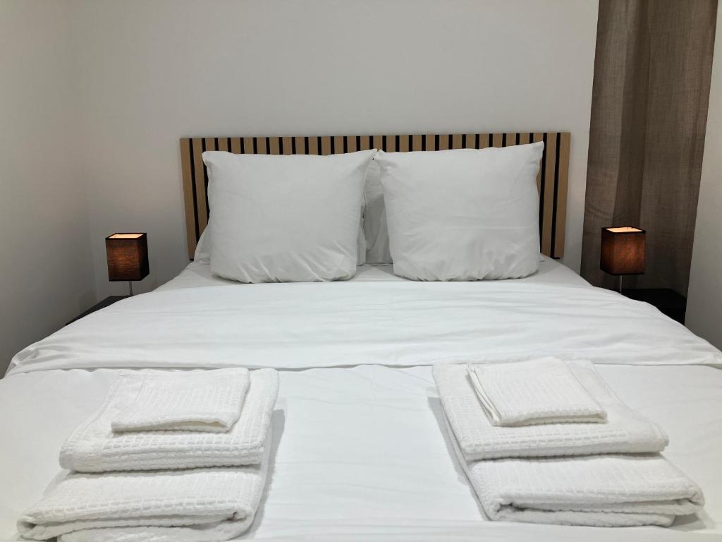 a bed with white sheets and pillows and two towels at Maison le Bac Paris Aparthotel in Paris