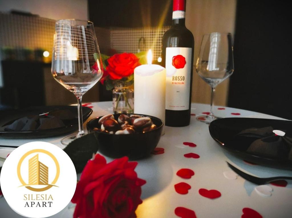 a table with a bottle of wine and a candle at Apartament Granatowy in Tychy