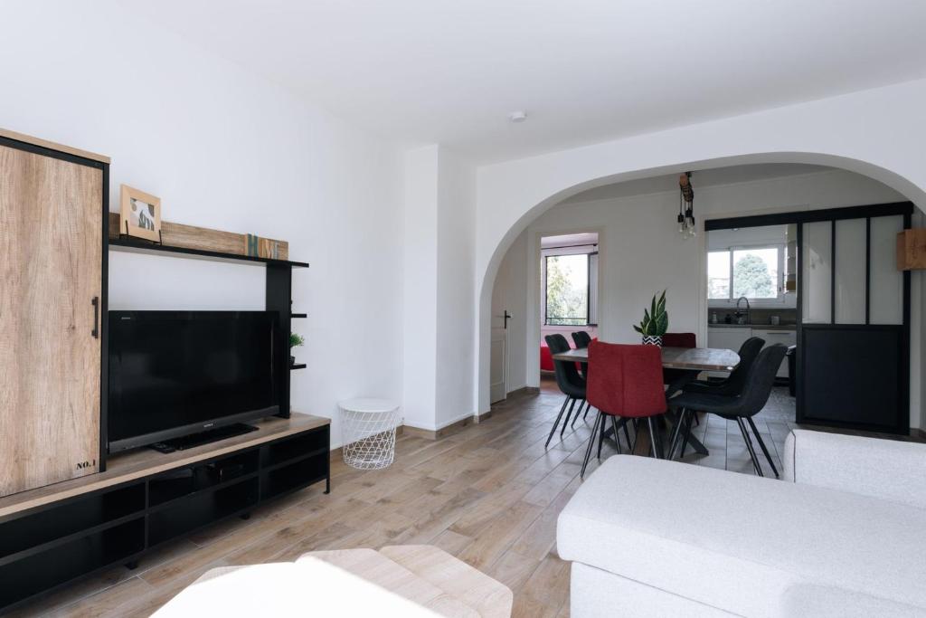 uma sala de estar com uma grande televisão e uma mesa em GuestReady - Calm and Charm near Bois de Boulogne em Saint-Cloud