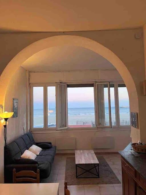a living room with a couch and a large window at Maison sur mer in Palavas-les-Flots