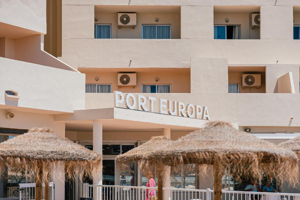 un hotel con sombrillas de paja delante de él en Port Europa en Calpe