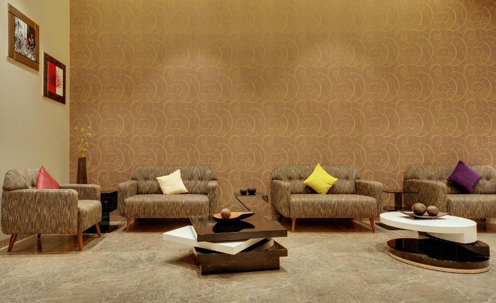 a waiting room with chairs and tables and a wall at Click Hotel Bhuj in Bhuj