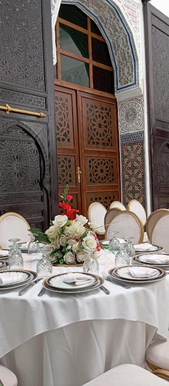 a table with white plates and flowers on it at Palais Chahd Luxury in Fez