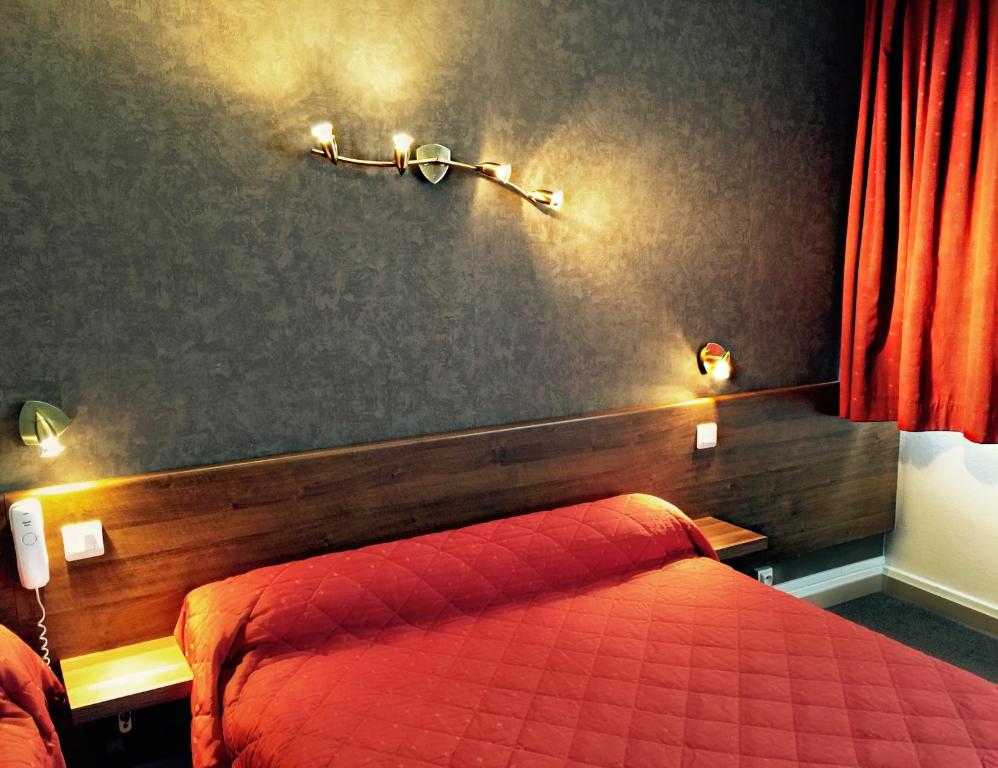 a bedroom with a bed and two lights on the wall at Hotel Saint-Aignan in Orléans