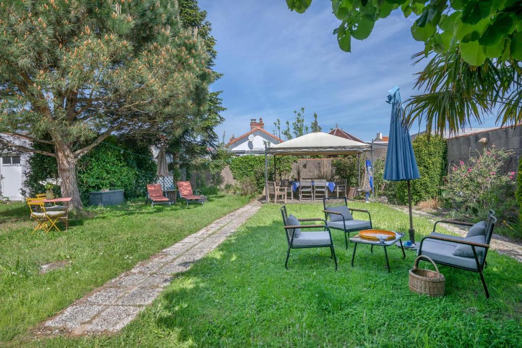 a yard with chairs and a table and an umbrella at Maison avec jardin à 200m de la mer à La Bernerie in La Bernerie-en-Retz