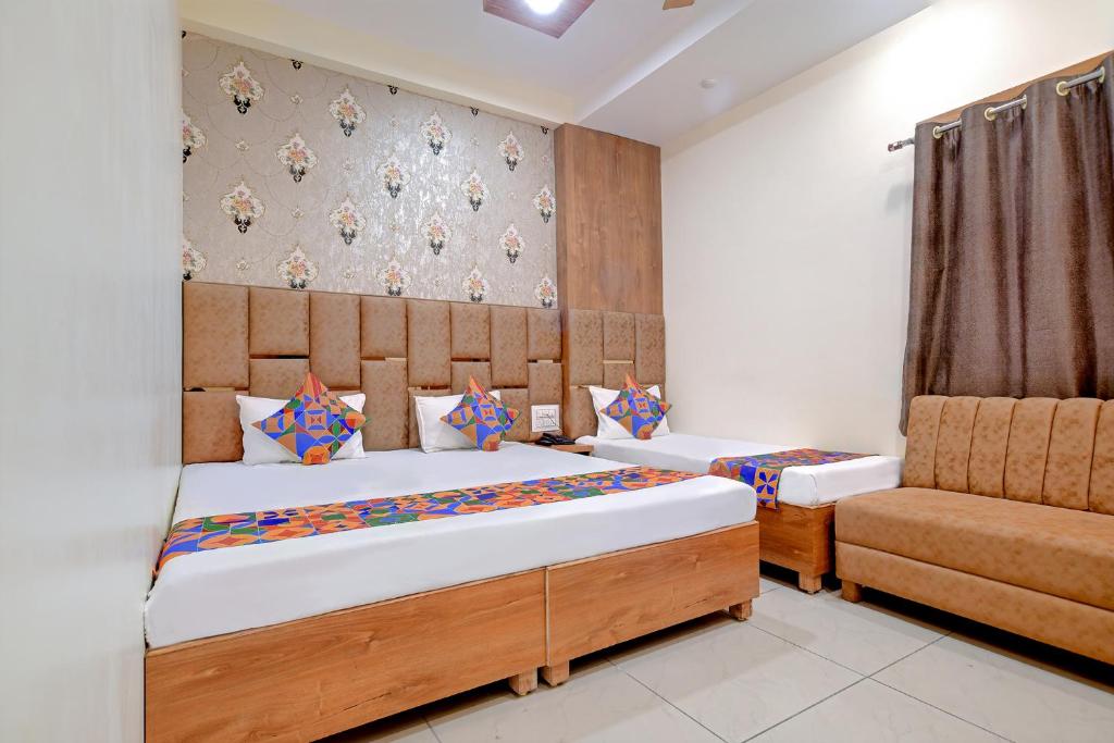 a bedroom with two beds and a chair at FabExpress SK Prime in Ujjain