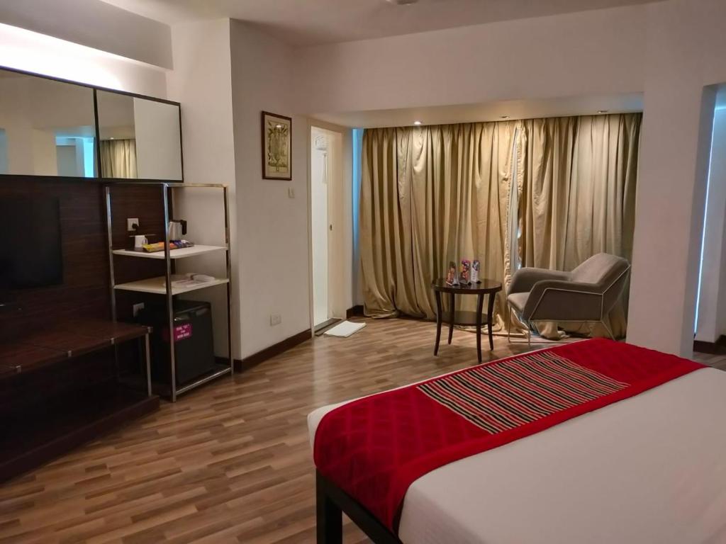 a bedroom with a bed and a chair and a desk at Regenta Place Bangalore, Cunningham Road in Bangalore