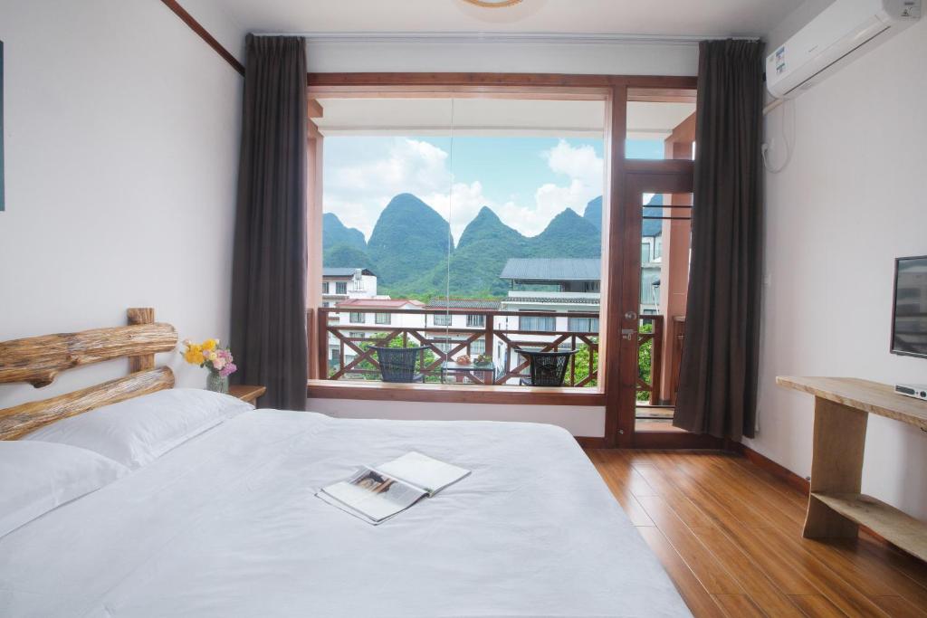 a bedroom with a bed with a book on it at Yangshuo Xiao Long River Hotel in Yangshuo