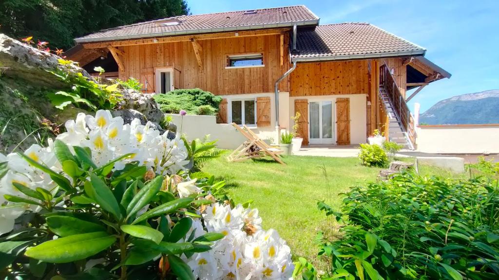 uma casa de madeira com flores brancas em frente em VUE LAC LODGES em Sévrier