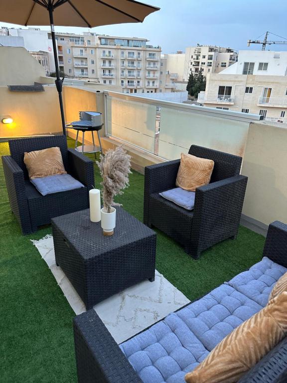 Un patio con sillas y mesas y una sombrilla. en Luxury penthouse in Sliema, en Sliema