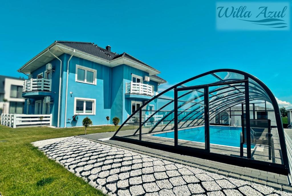 a blue house with a swimming pool in front of it at Willa Azul - Podgrzewany basen, klimatyzacja w całym obiekcie in Sarbinowo