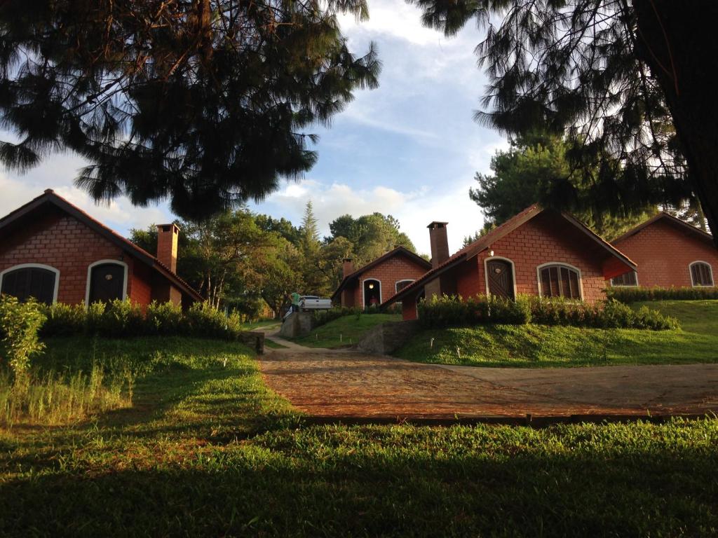 a red brick house with a dirt road in front at Emy Pousada in Monte Verde