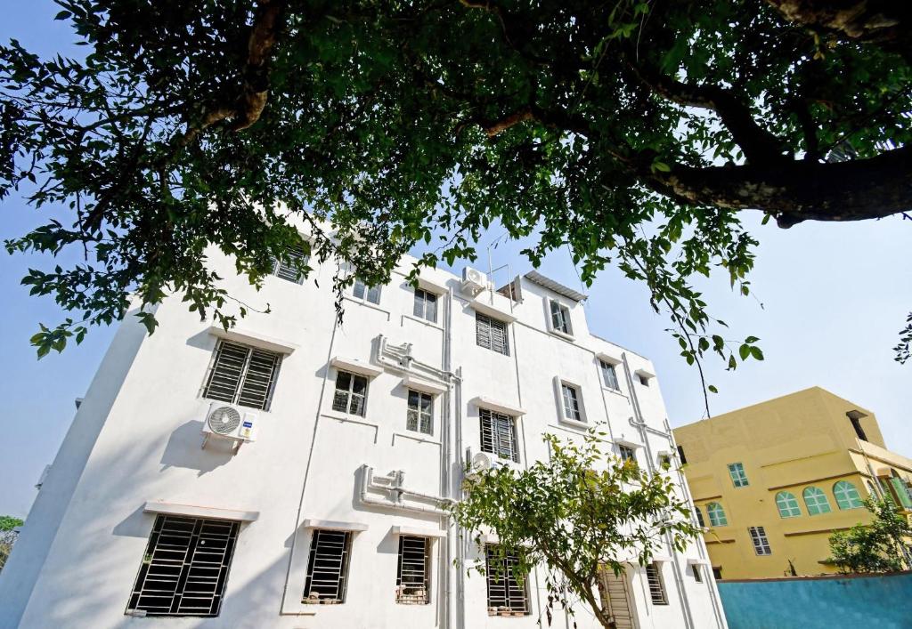 een wit gebouw met ramen en een boom bij OYO Hotel Grand Eden in Calcutta