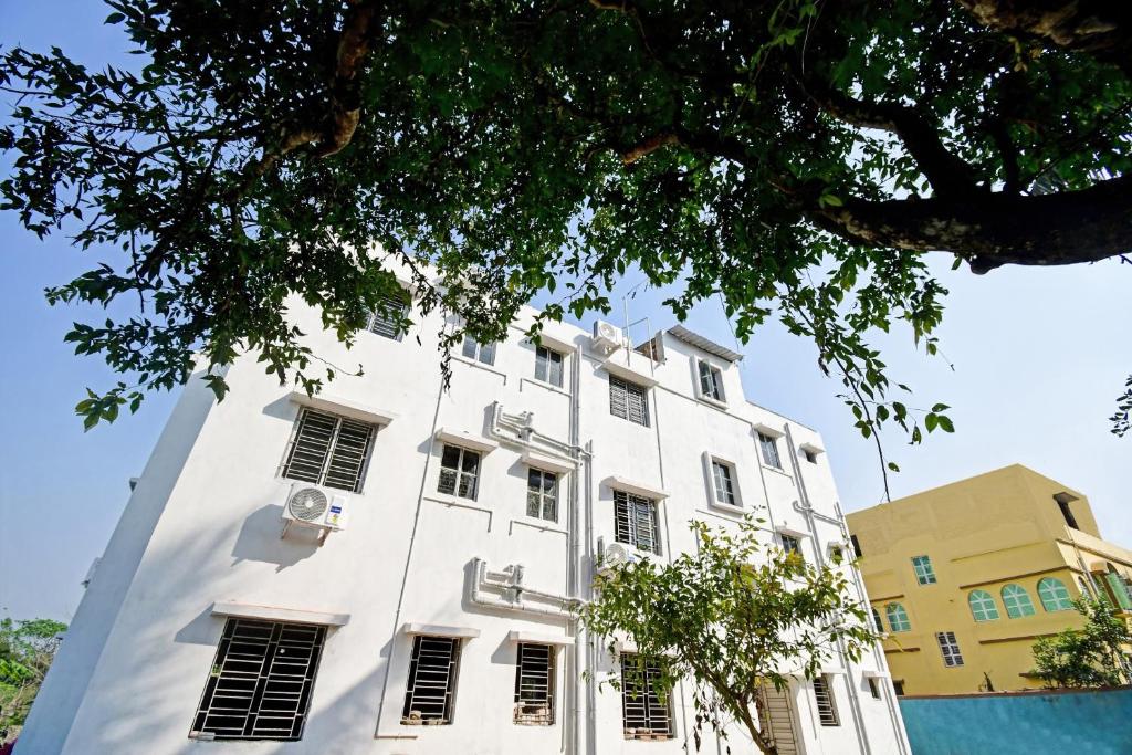 - un bâtiment blanc avec des fenêtres et un arbre dans l'établissement OYO Hotel Grand Eden, à Kolkata