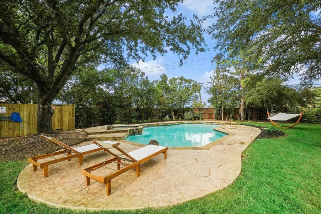 una piscina con due panchine in un cortile di Tropical Pool Oasis - 5 BR Foosbal Cinema a Flower Mound