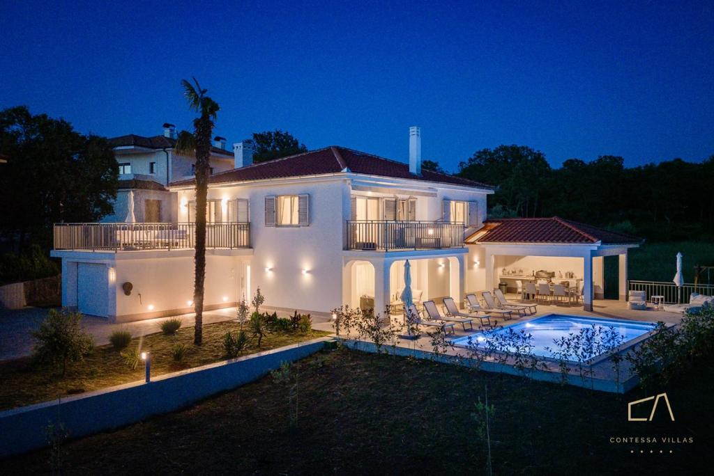 una gran casa blanca con piscina por la noche en Villa Palma en Malinska