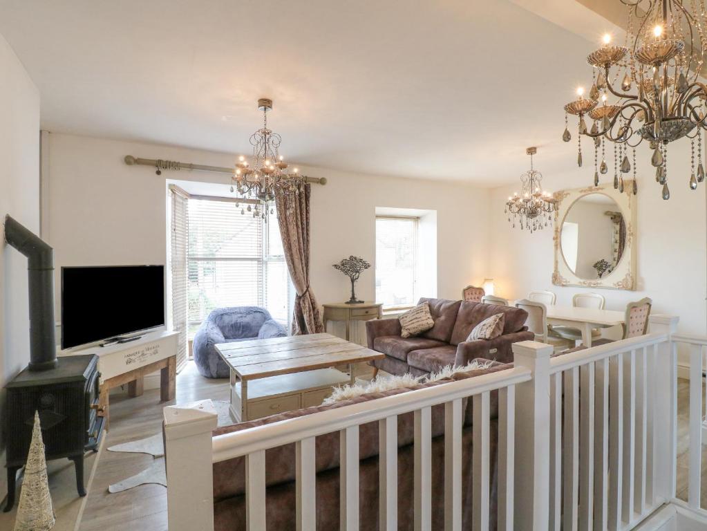 Una sala de estar con un sofá y un televisor. en Matlock Maisonette, en Matlock