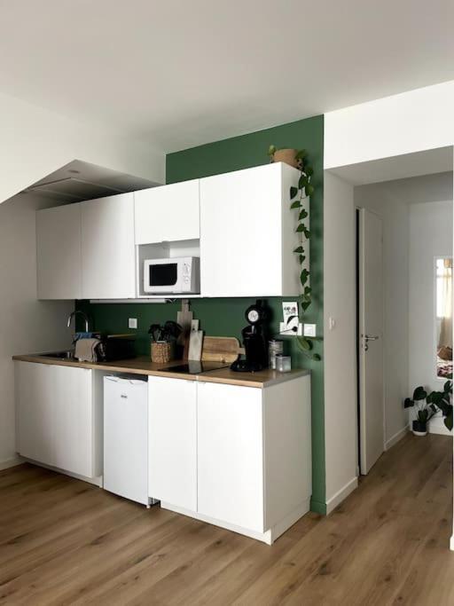 a kitchen with white cabinets and a green wall at Appartement en hyper centre in Étaples