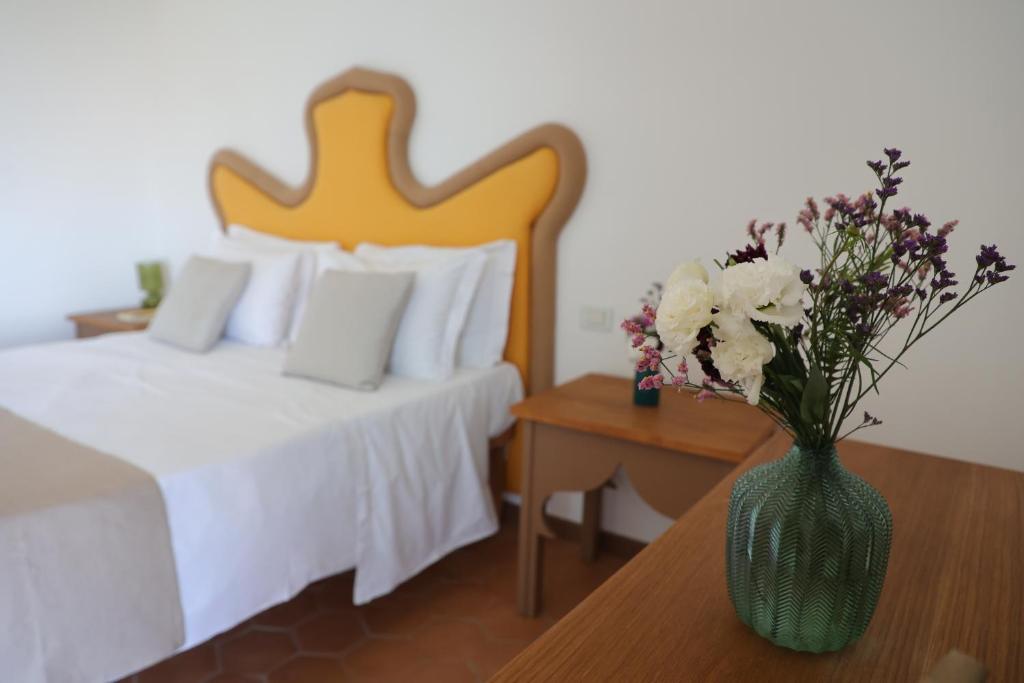 una camera da letto con un letto e un vaso con fiori su un tavolo di Villa Puolo - With Private Sea Access a Sorrento