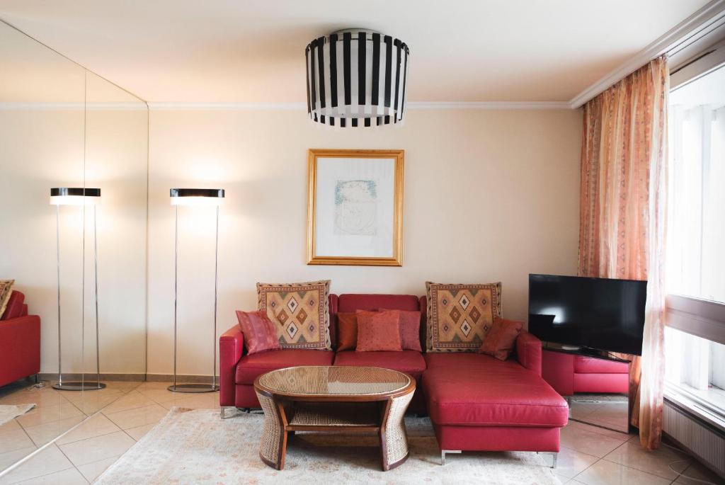 un soggiorno con divano rosso e TV di Residenza Porto Fino App 7000 a Brissago