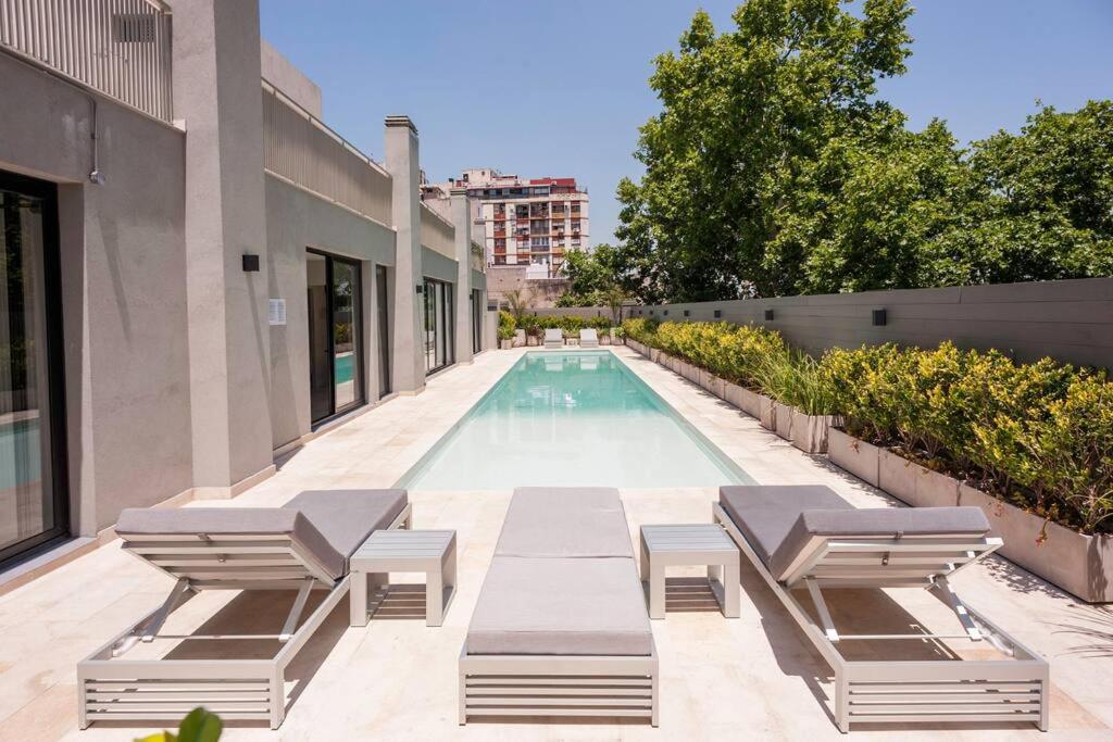a swimming pool with chaise lounge chairs next to a building at Premium Apt 2BR 24x7 San Telmo 300 Mb La Galerie in Buenos Aires