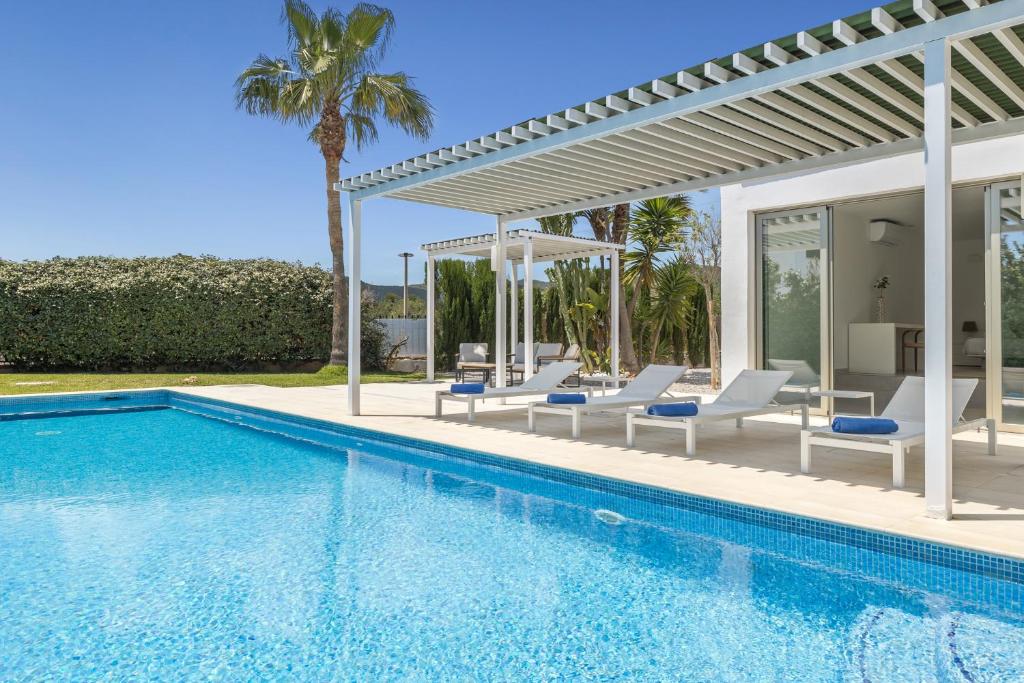 a pool with chairs and a pergola next to a house at Villa Marc II in Sant Jordi