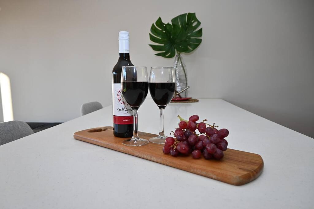 a bottle of wine and two glasses on a table at Mawson Red - Free Pool access -Onsite Parking-Netflix-5 mins to Mawson Interchange in Mawson Lakes