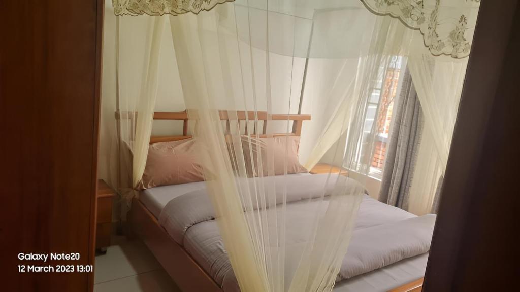 1 Schlafzimmer mit 2 Betten, weißen Vorhängen und einem Fenster in der Unterkunft Room in Guest room - Charming Room in Kayove, Rwanda - Your Perfect Getaway 