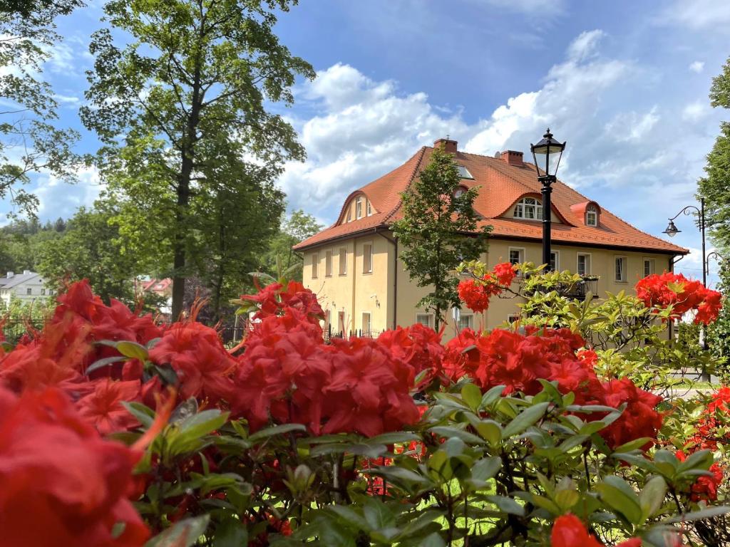 uma casa com flores vermelhas em frente em Rezydencja Grawert Boutique & Spa em Lądek-Zdrój