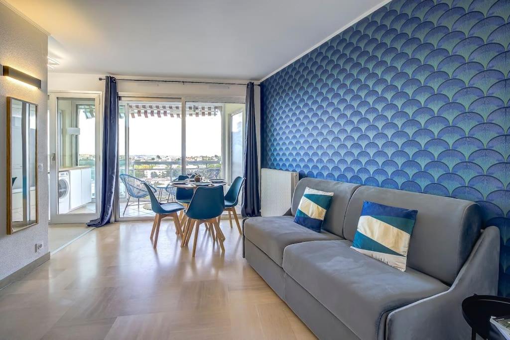 un salon avec un canapé et une table avec des chaises dans l'établissement Studio vue mer, piscine - tennis, à Antibes