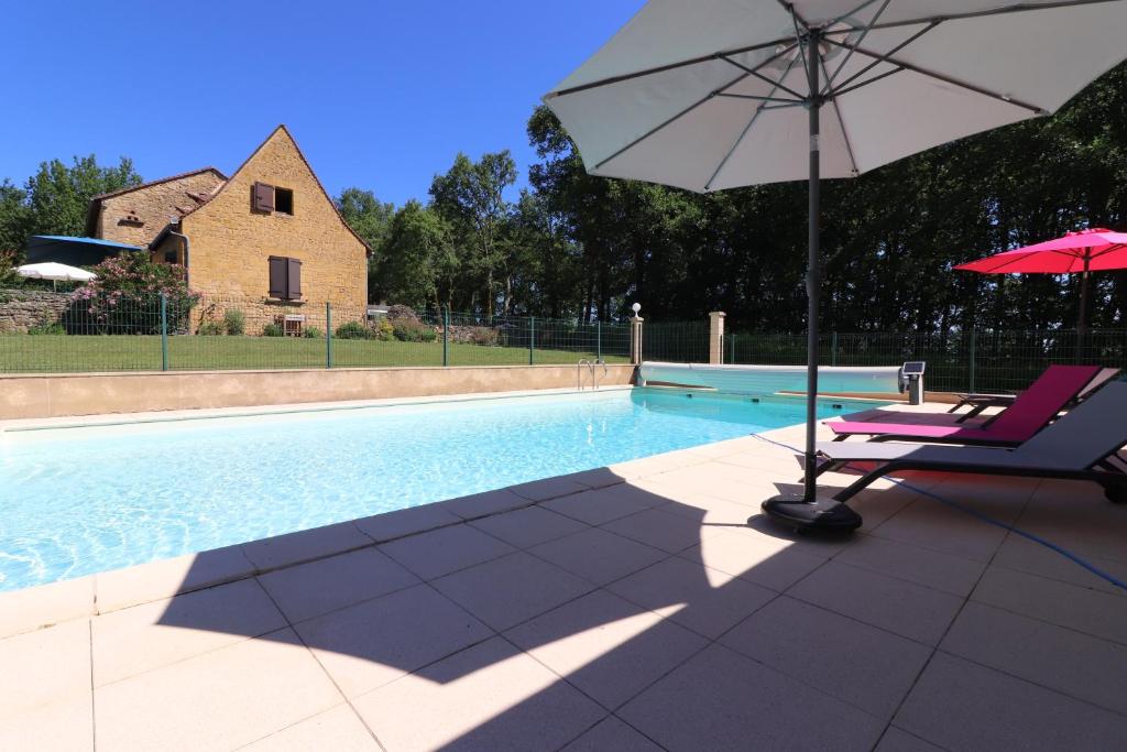 una silla y una sombrilla junto a la piscina en Au Bonheur d'Angeline, en Castelnaud La Chapelle