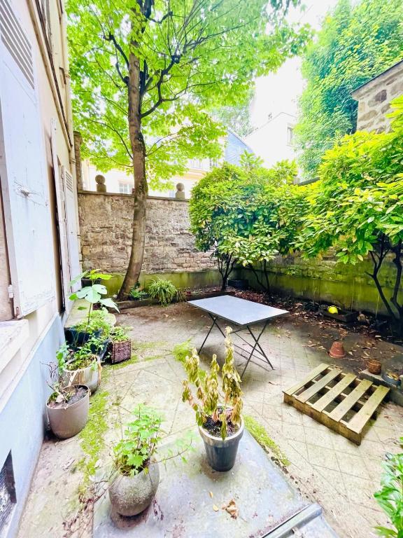 une terrasse avec une table et des plantes en pot dans l'établissement Ravière, à Paris