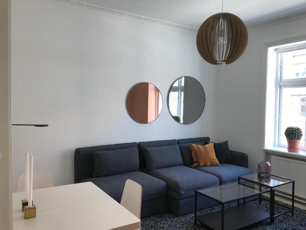 a living room with a blue couch and mirrors at Nice 1-bed in Østerbro - 279 in Copenhagen
