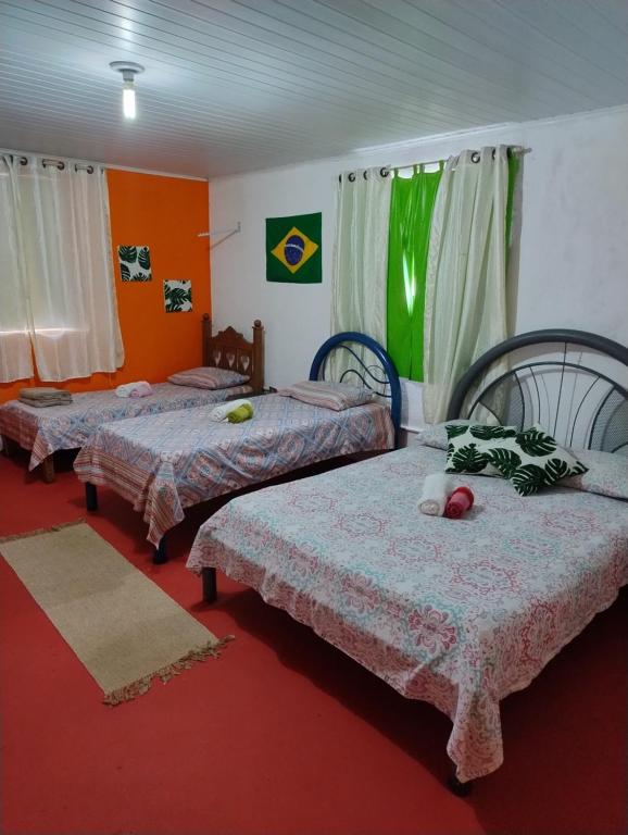 three beds in a room with red carpet at Perto Do Aeroporto De Salvador - Dona Pitanga Hostel in Lauro de Freitas