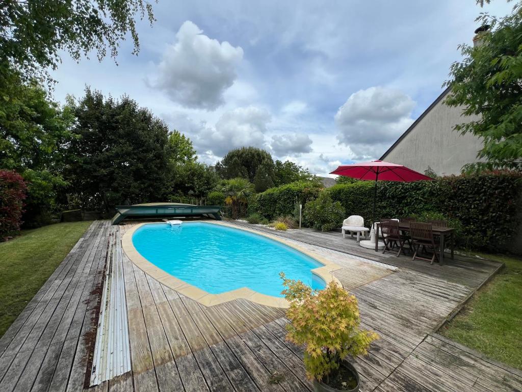 une piscine dans une cour arrière avec une table et des chaises dans l'établissement Maison familiale Coeur de Loire, à Montlouis-sur-Loire