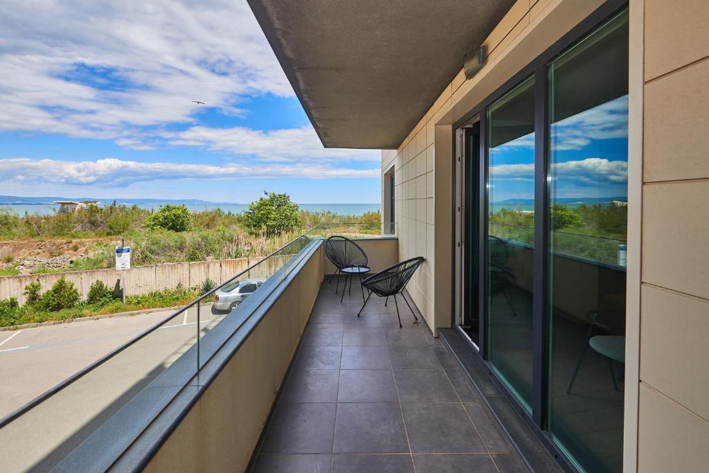a balcony with two chairs and a view at Luxury Sea View Apartment in Pomorie in Pomorie