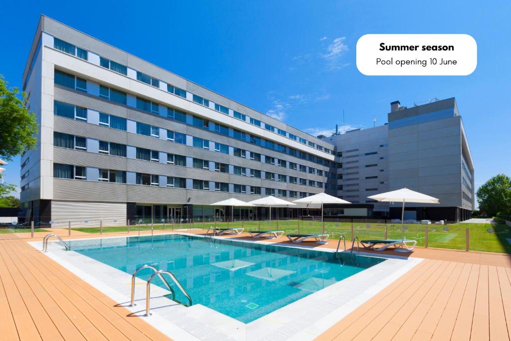 un hotel con piscina frente a un edificio en Axor Barajas en Madrid