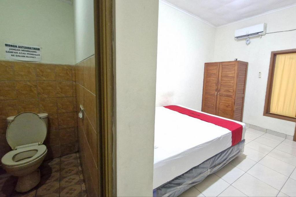 un piccolo bagno con letto e servizi igienici di Reddoorz at Griya Kampar Madiun a Madiun