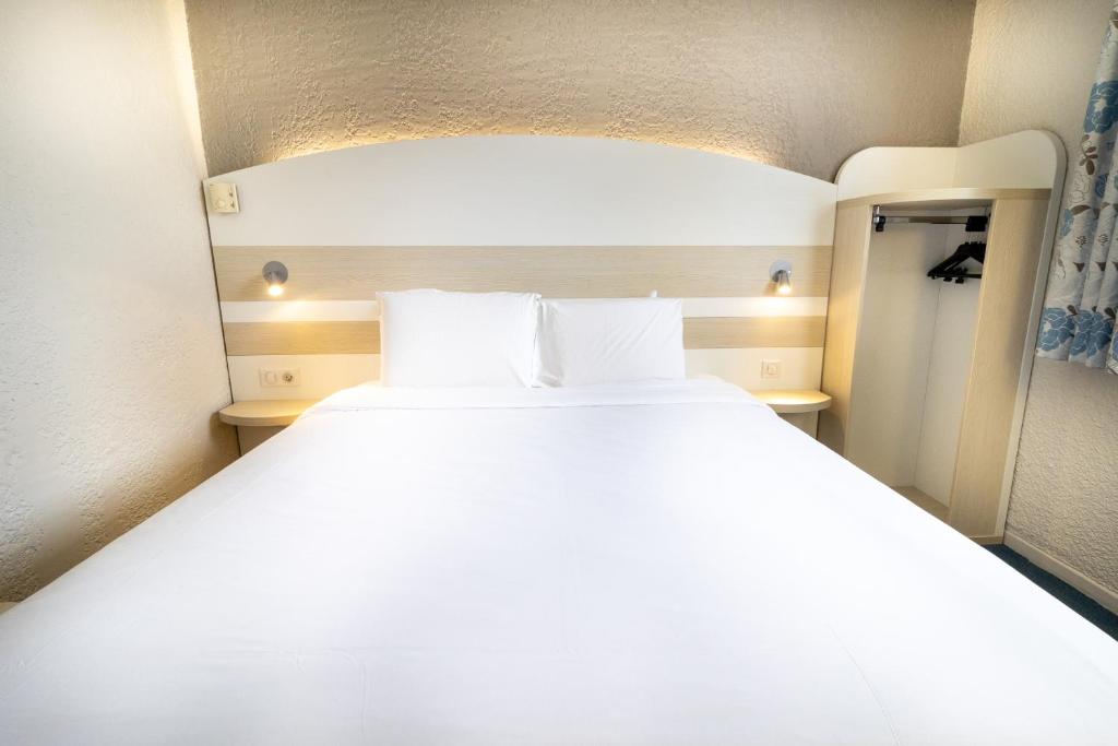 a large white bed in a small room at Kyriad Auxerre Appoigny in Appoigny