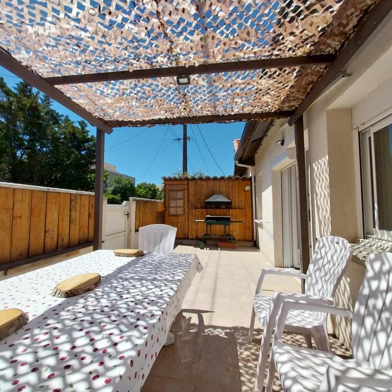d'une terrasse avec une table et des chaises et un plafond en verre. dans l'établissement Coquette maison, 2 chambres mansardées, Narbonne Plage, à Narbonne-Plage