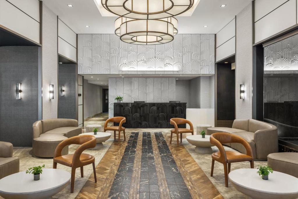 a lobby with couches and chairs and a chandelier at The Muse New York in New York