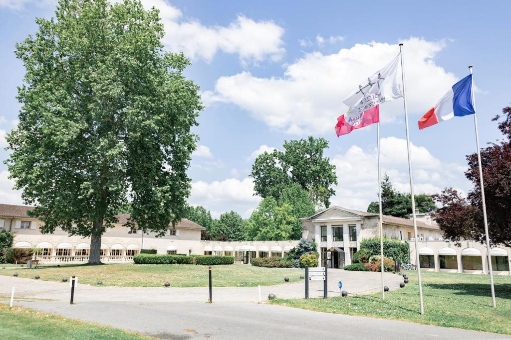 tres banderas volando delante de un edificio en Relais de Margaux - Hôtel & Spa, en Margaux