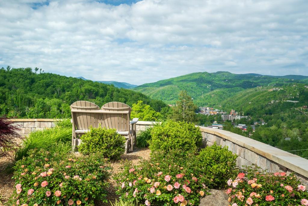 a wooden bench sitting on top of a hill with flowers at Just Perfect By Stony Brook Cabins in Gatlinburg