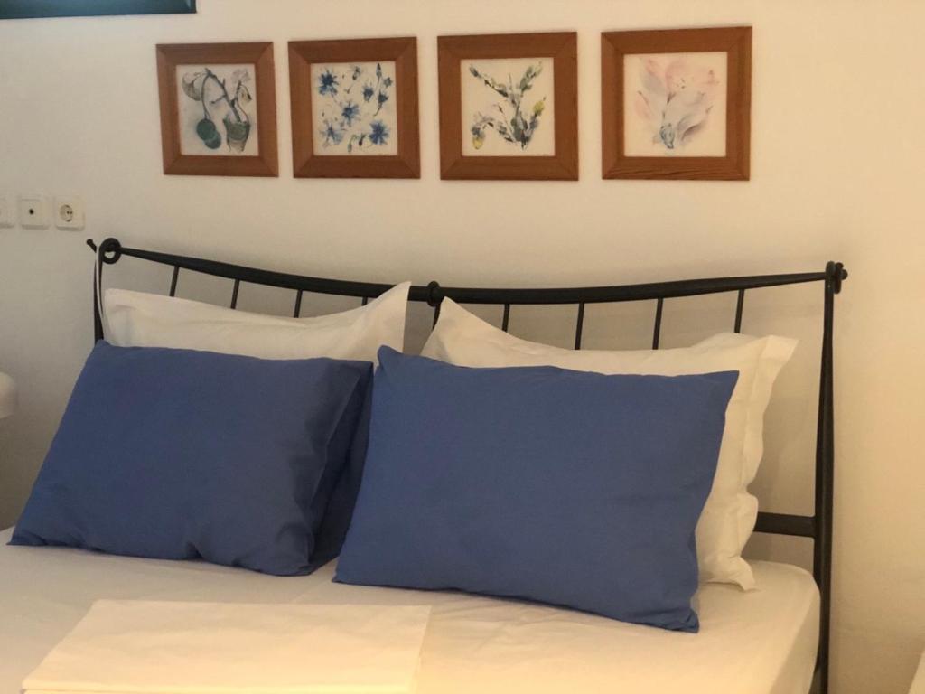 1 cama con almohadas azules y blancas y cuadros enmarcados en Sideroporta castle Náfpaktos, en Nafpaktos