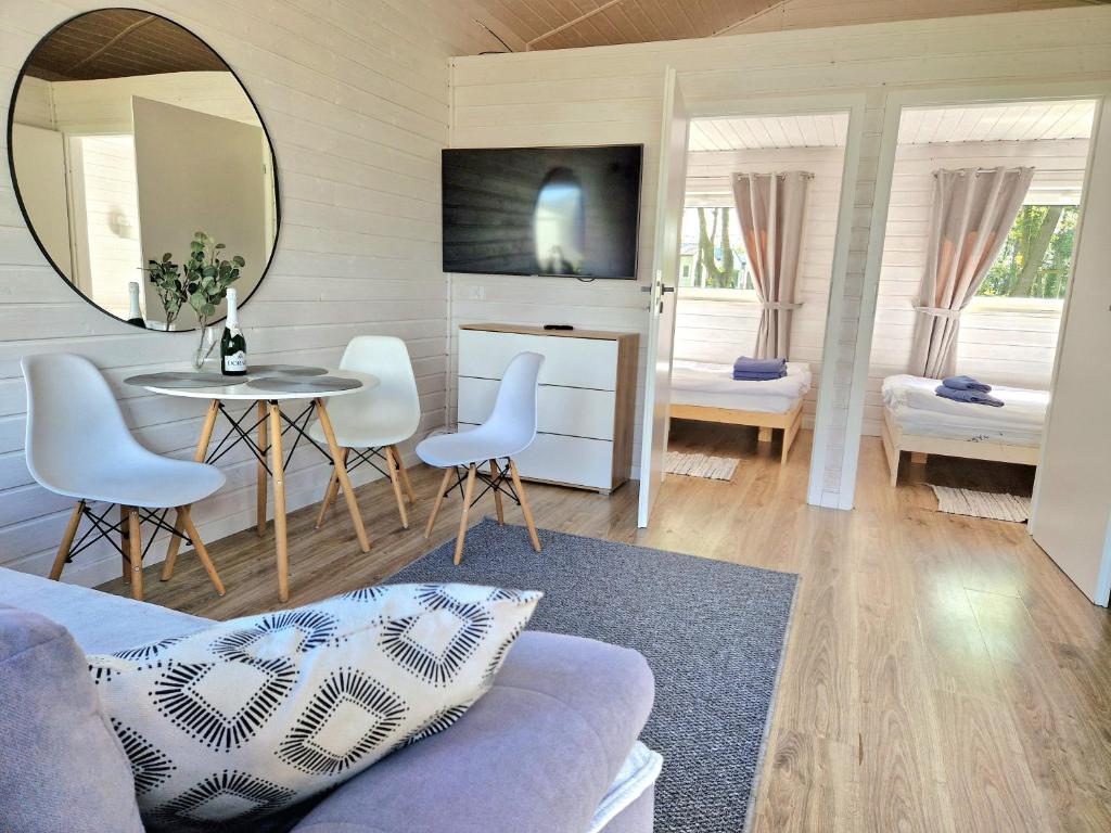 a living room with a table and a mirror at Lumi Resort Domki letniskowe z podgrzewanym basenem in Rewal