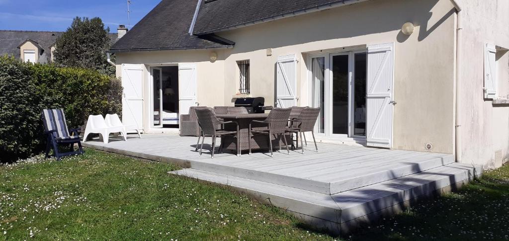 une terrasse en bois avec une table et des chaises dessus dans l'établissement Résidence 250 m plage de Guidel, à Guidel