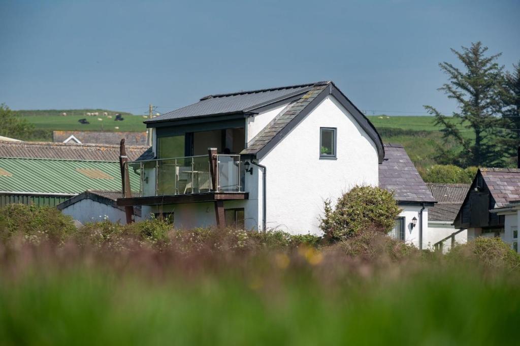 a white house with a balcony on top of it at Glan Yr Afon in Llanrhyddlad